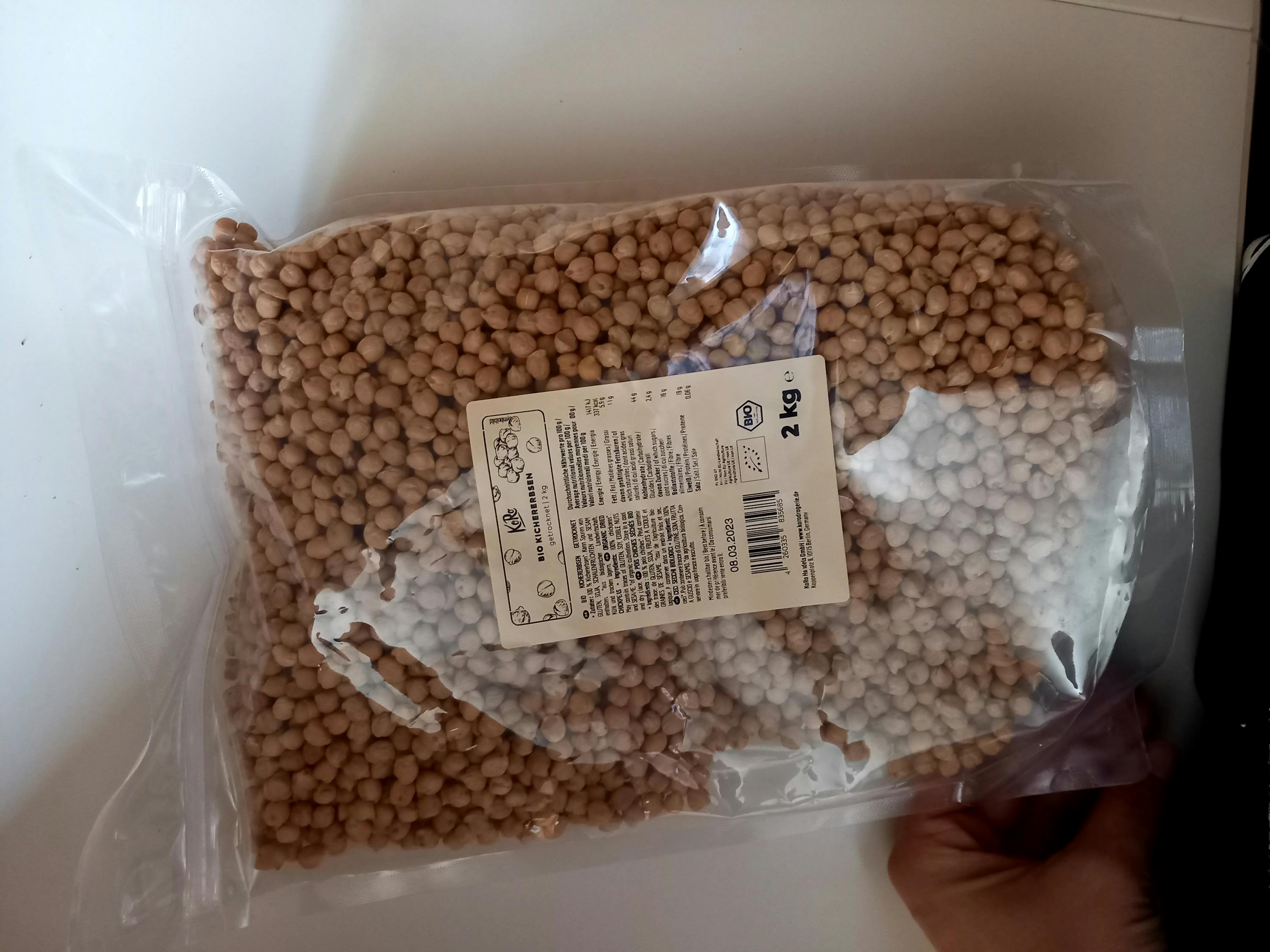 une personne tient un sac de pois 2 kg