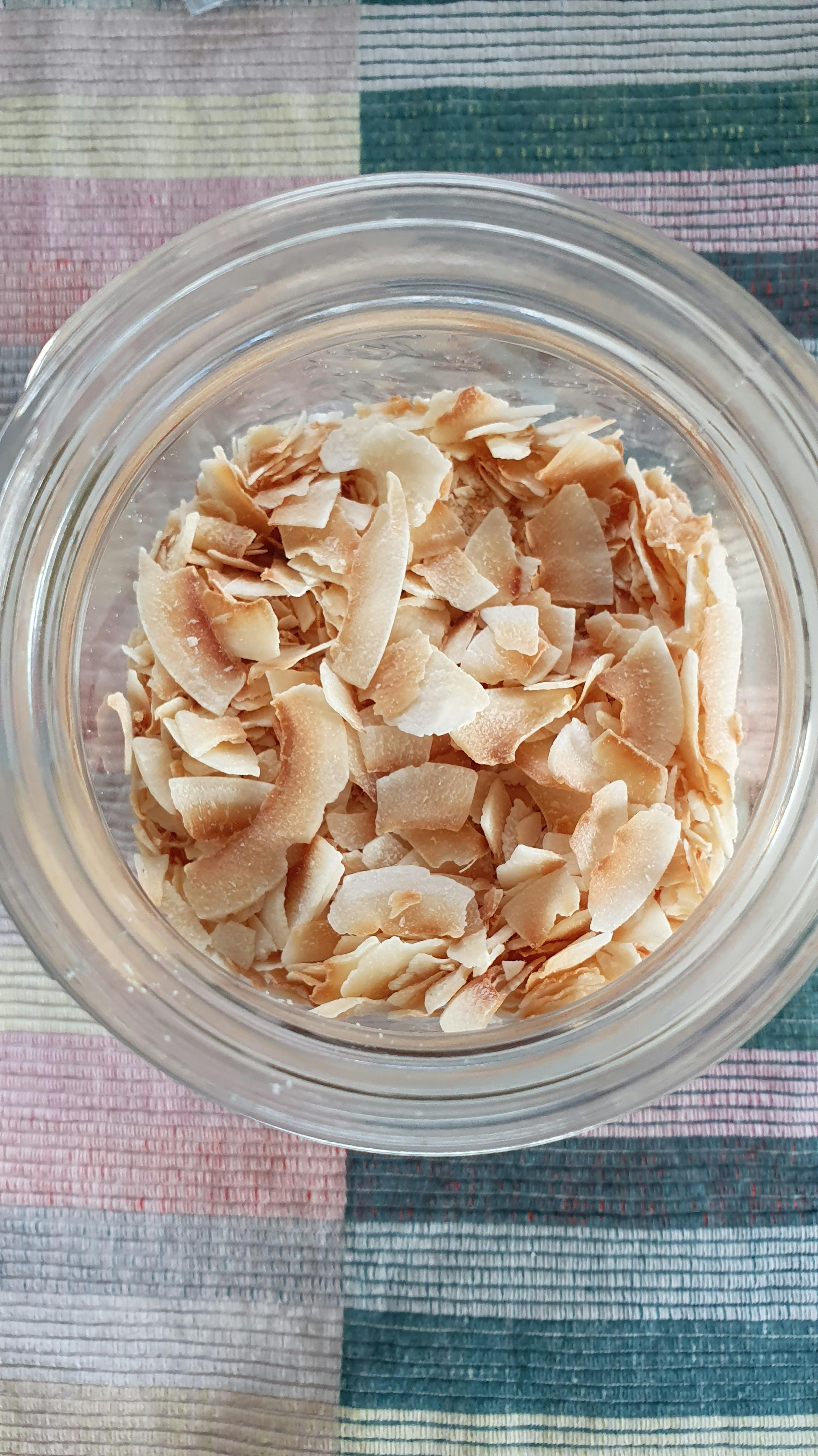 a glass jar filled with sliced coconut on a striped cloth