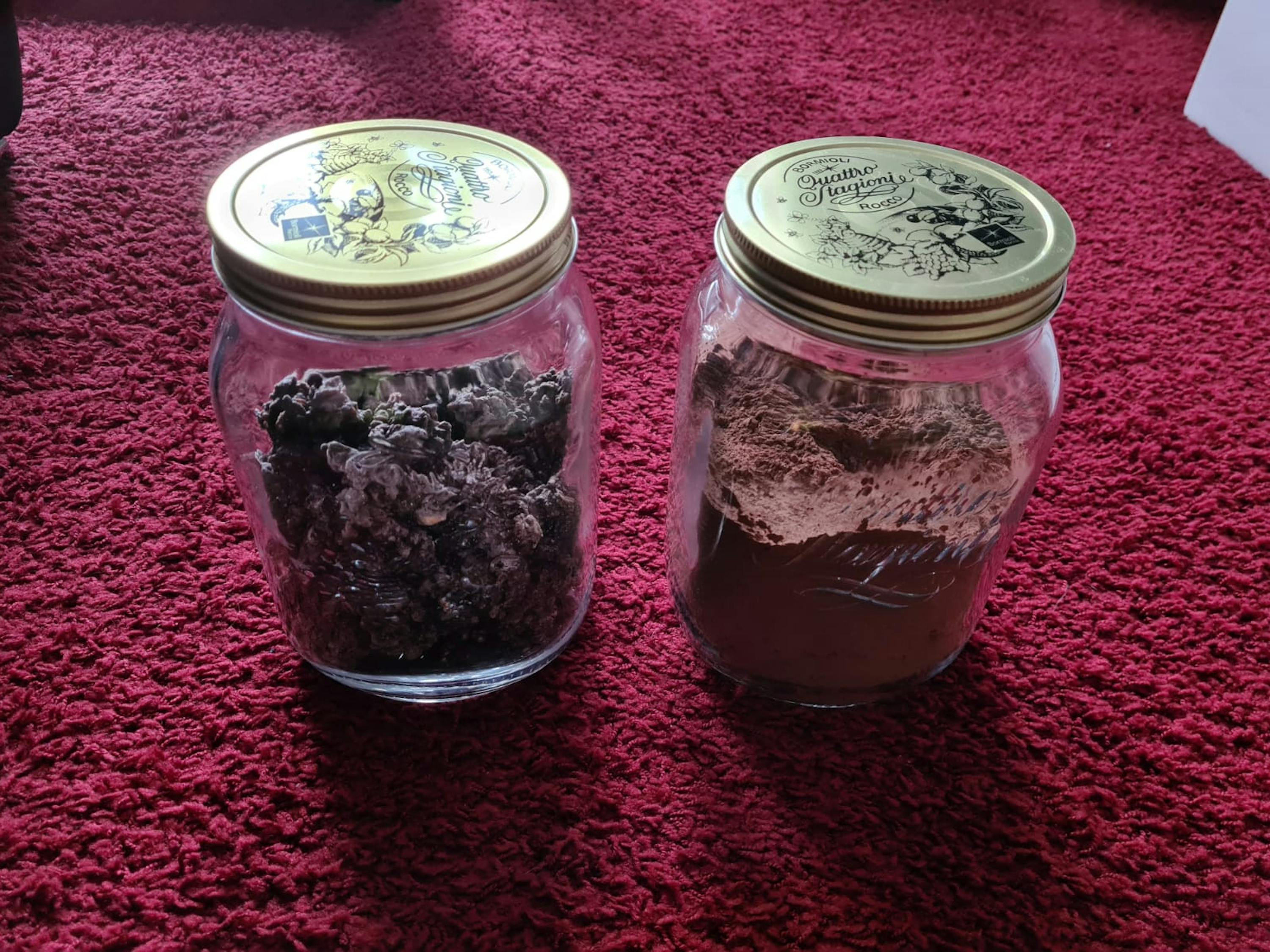 deux bocaux en verre avec des couvercles dorés sont posés sur un tapis rouge