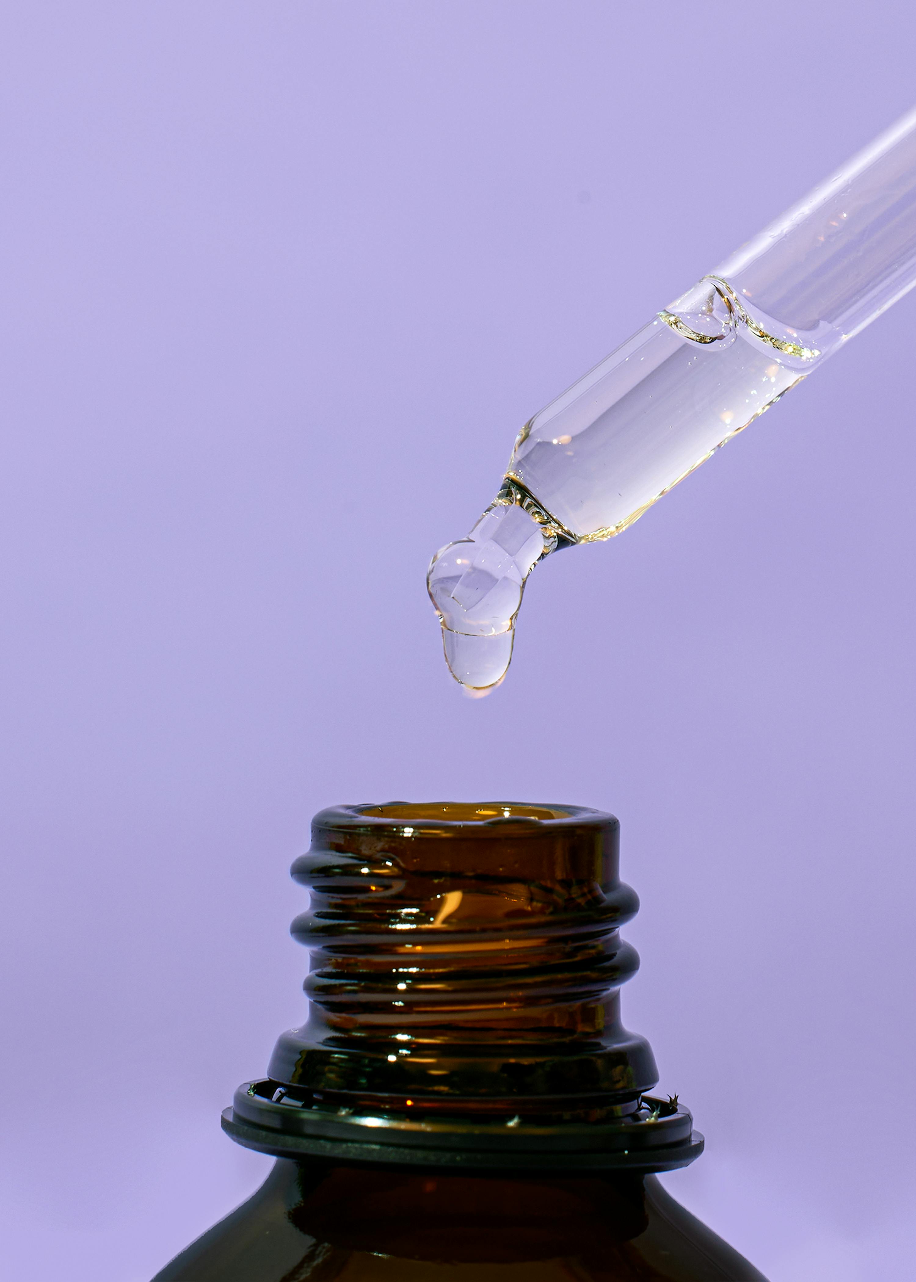 eine Tropfpipette gießt eine Flüssigkeit in eine Glasflasche