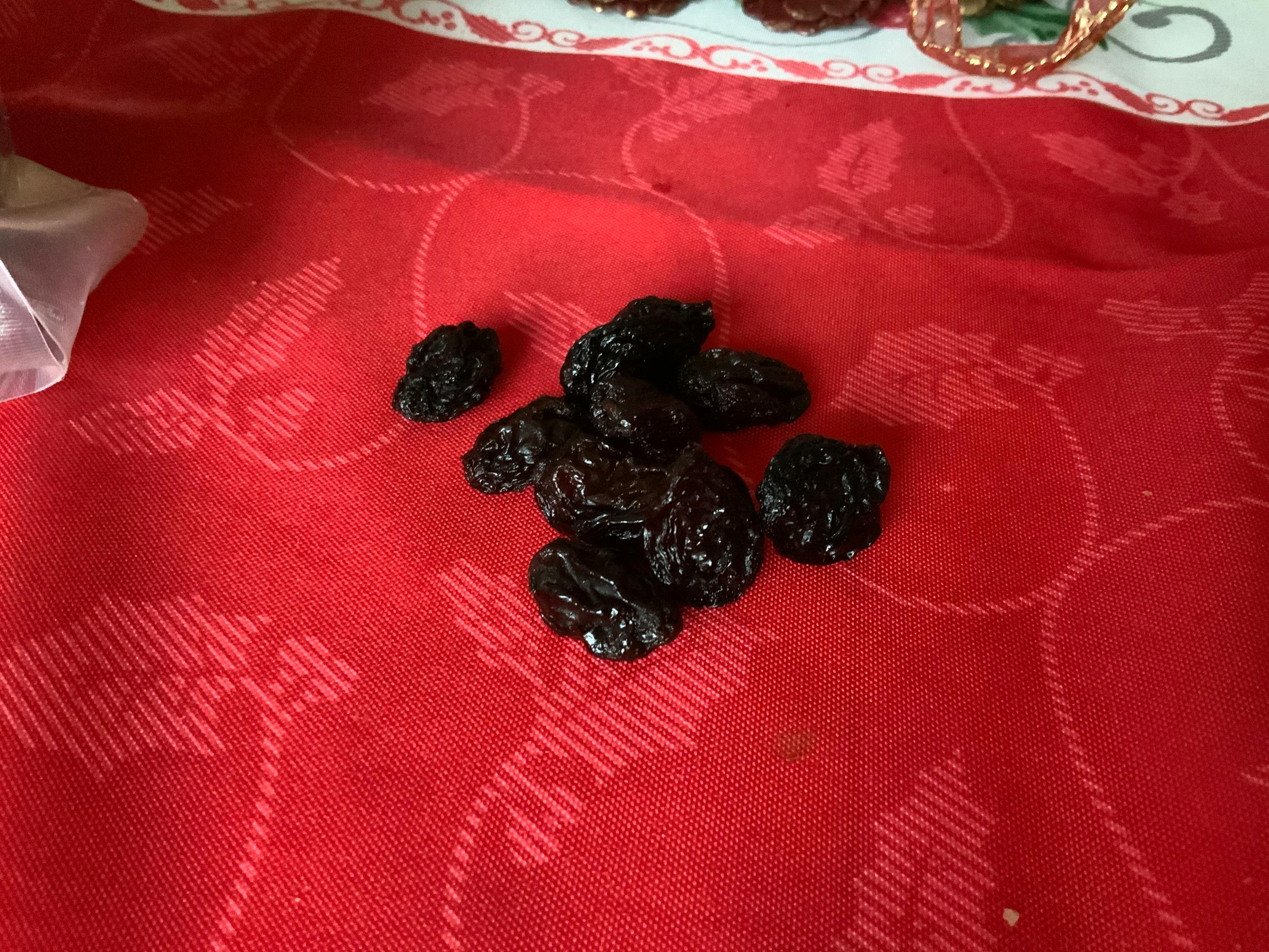 ein Haufen schwarzer Rosinen liegt auf einem roten Tischtuch