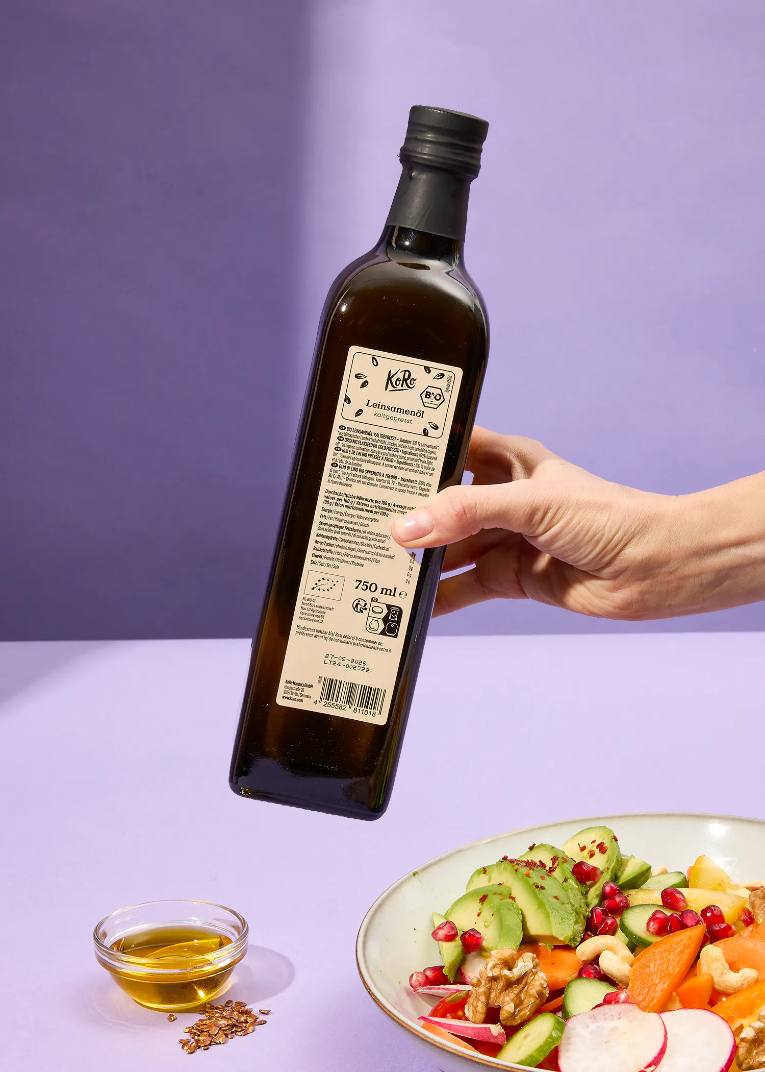 Eine Person hält eine Flasche kaltes Leinsamenöl in der Hand