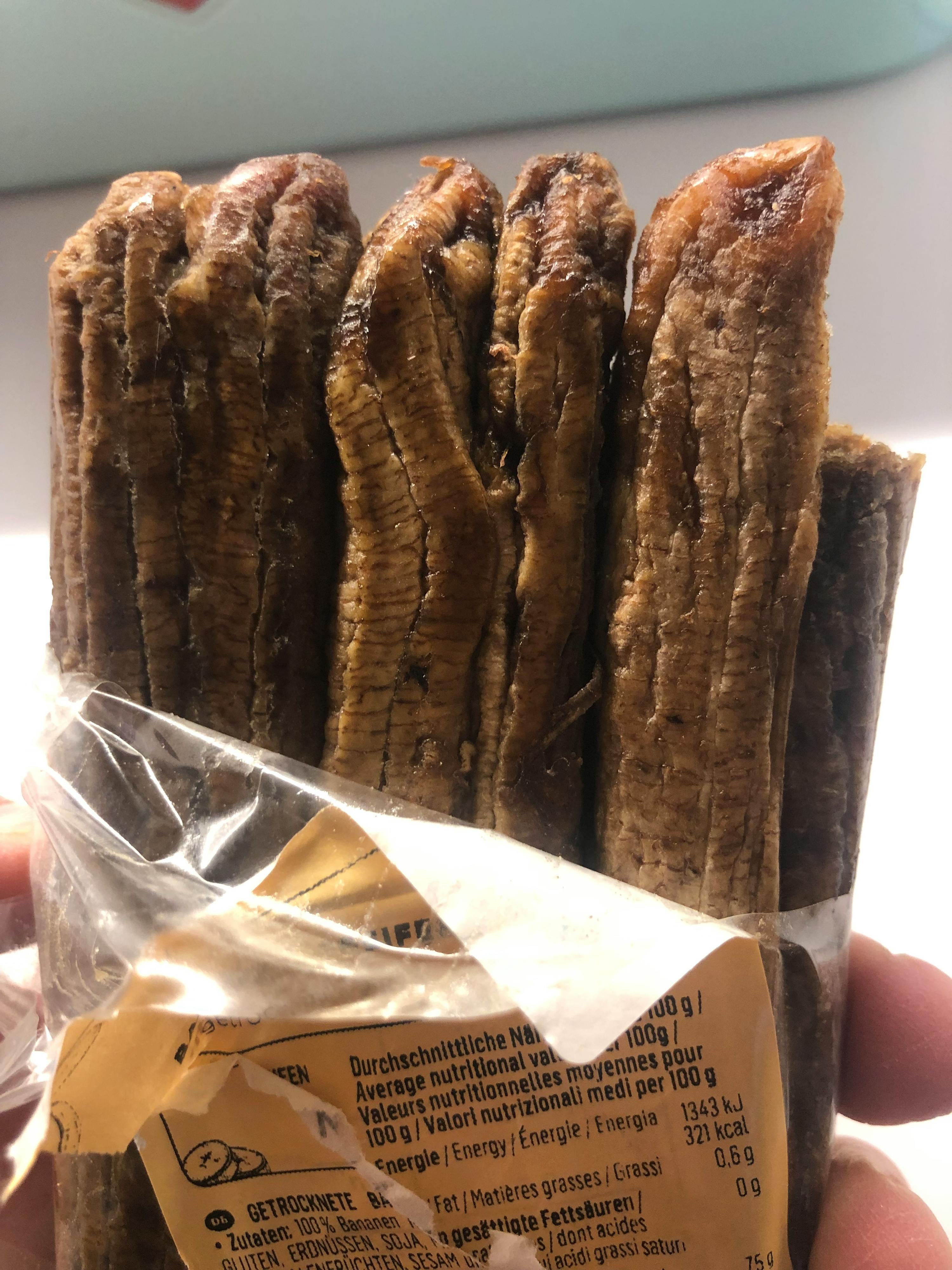 a person is holding a bag of dried bananas with a label that says " average nutritional value per 100 g "