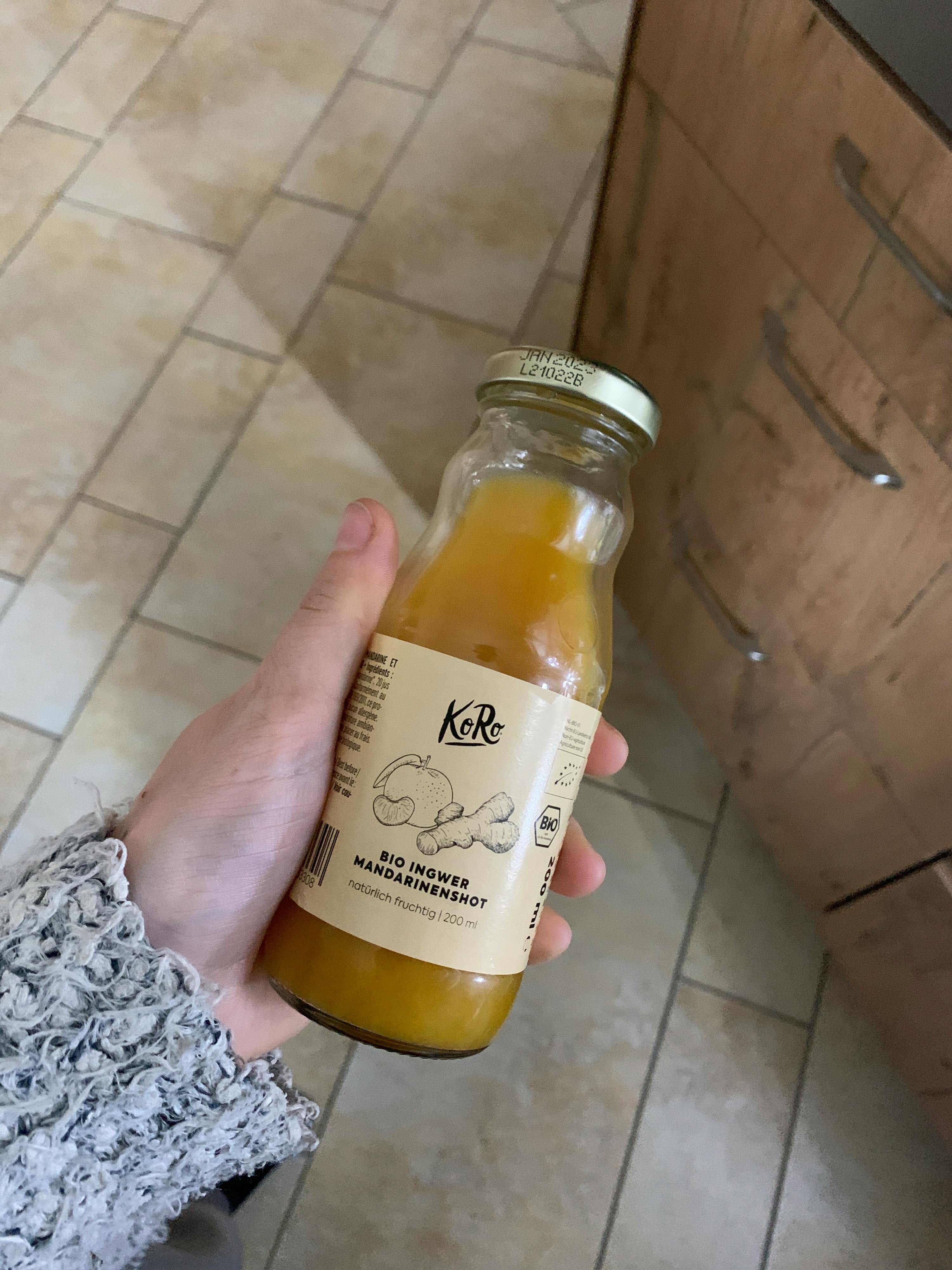 une personne tient une bouteille de jus de gingembre et de mangue
