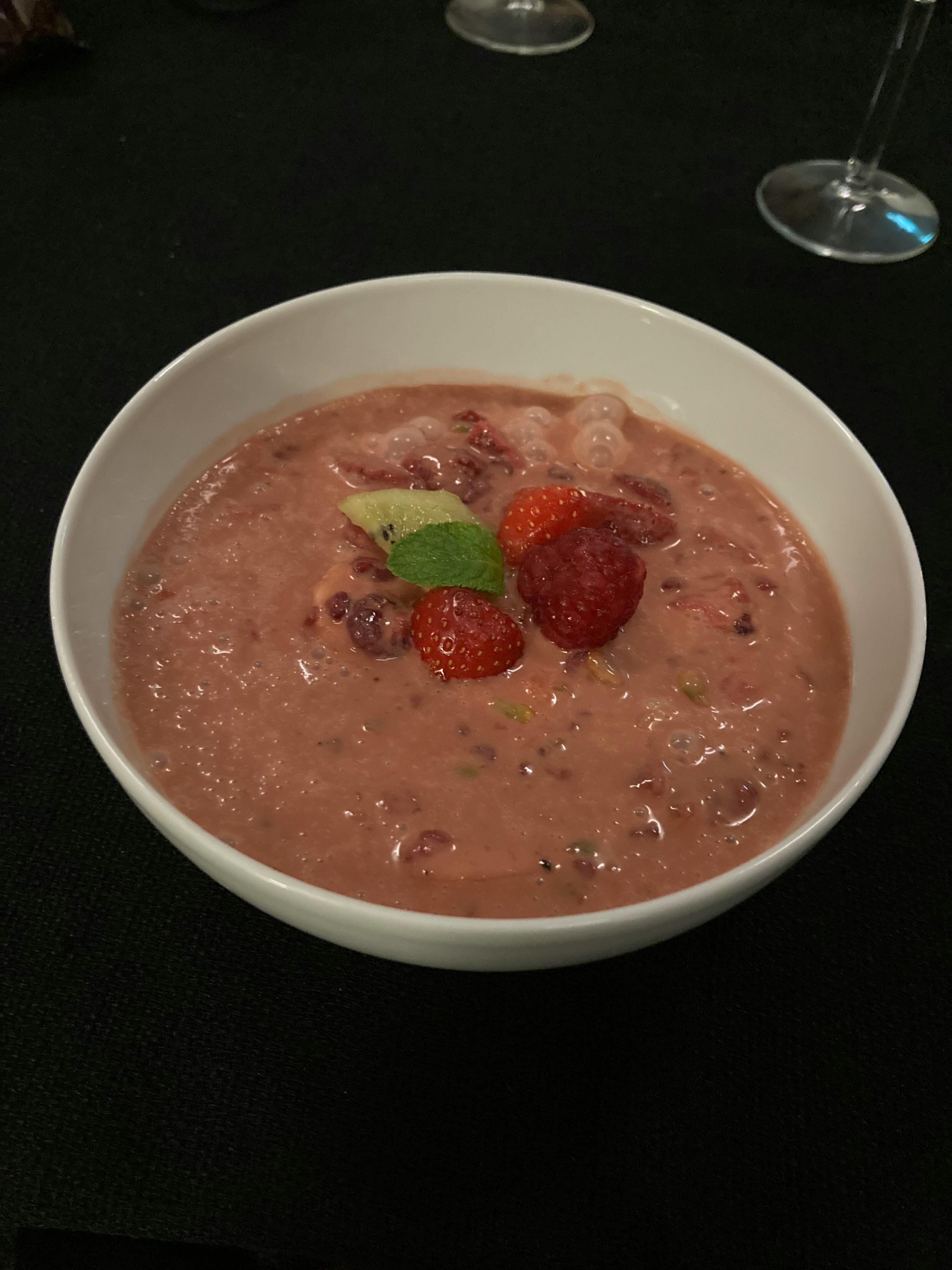 una ciotola di zuppa rosa con fragole e kiwi sopra