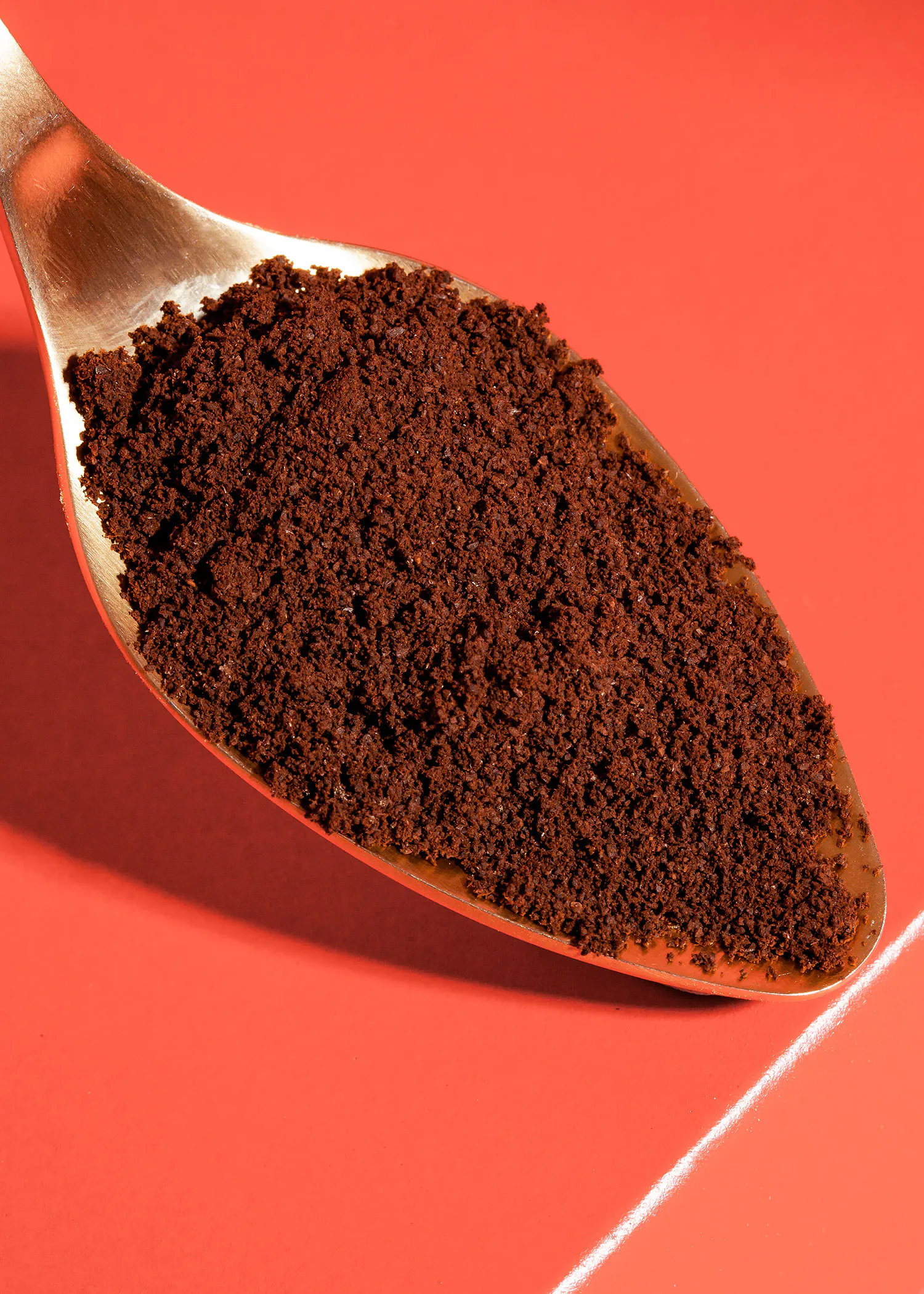 une cuillère remplie de poudre de café sur fond rouge