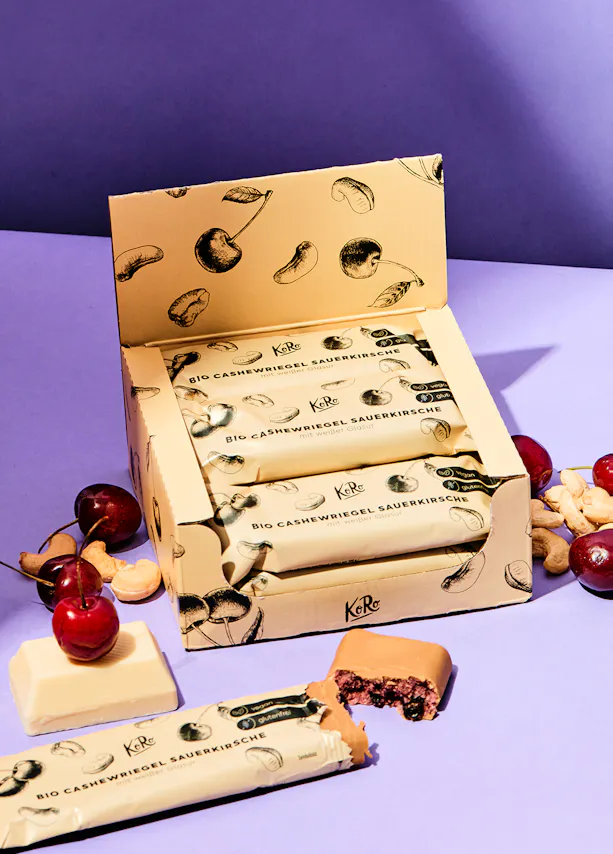 une boîte de barres de céréales avec des cerises et des noix dessus