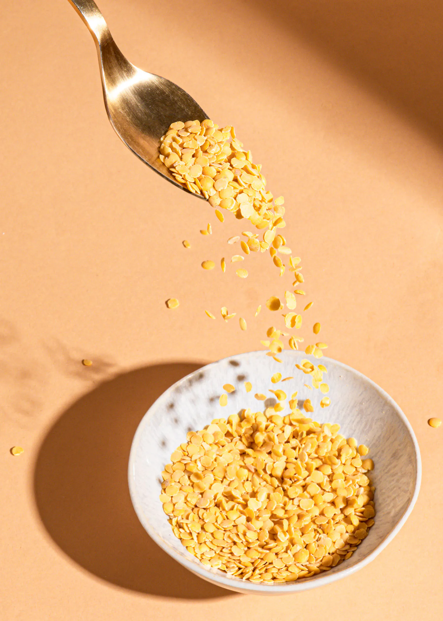 eine Schüssel mit gelben Bohnen wird mit einem Löffel gefüllt