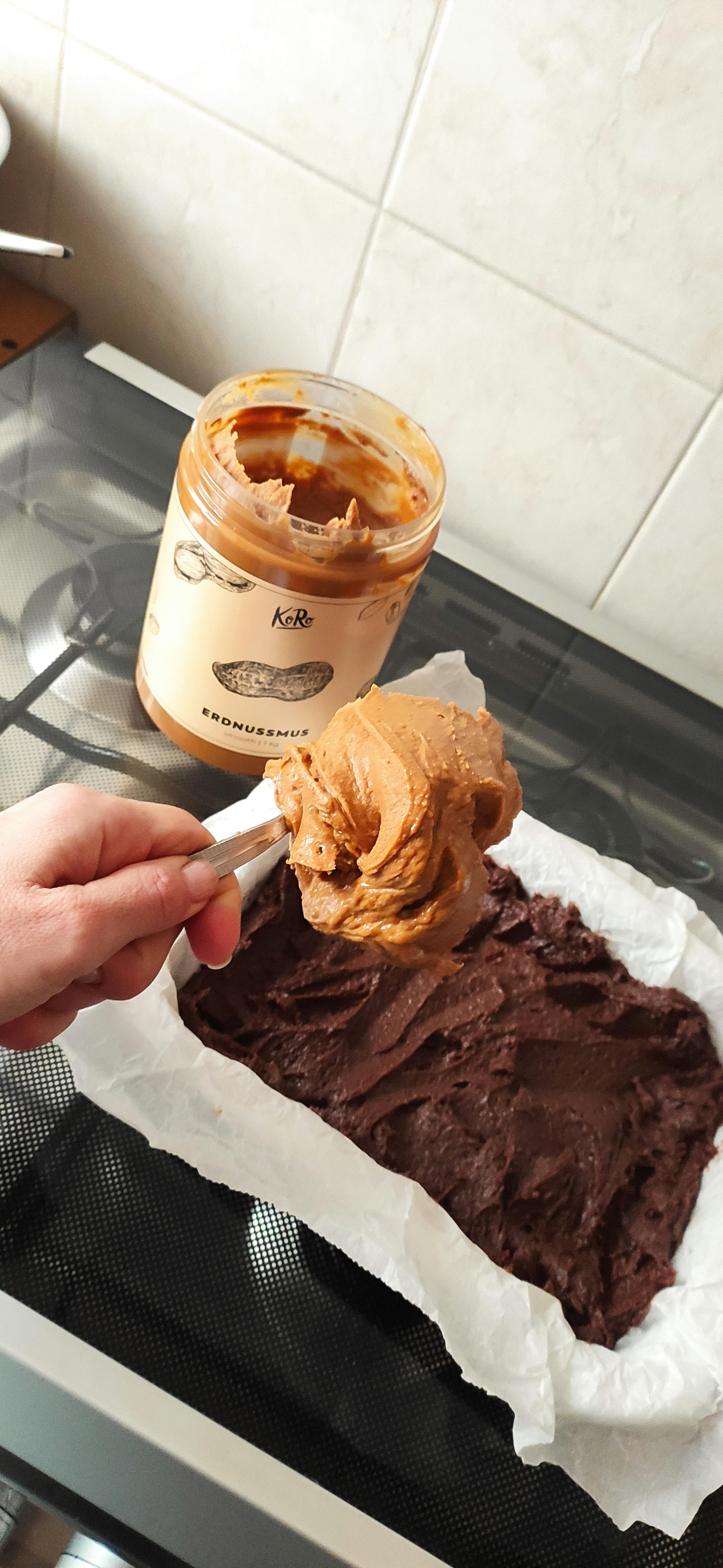 una persona tiene in mano un cucchiaio di burro di arachidi