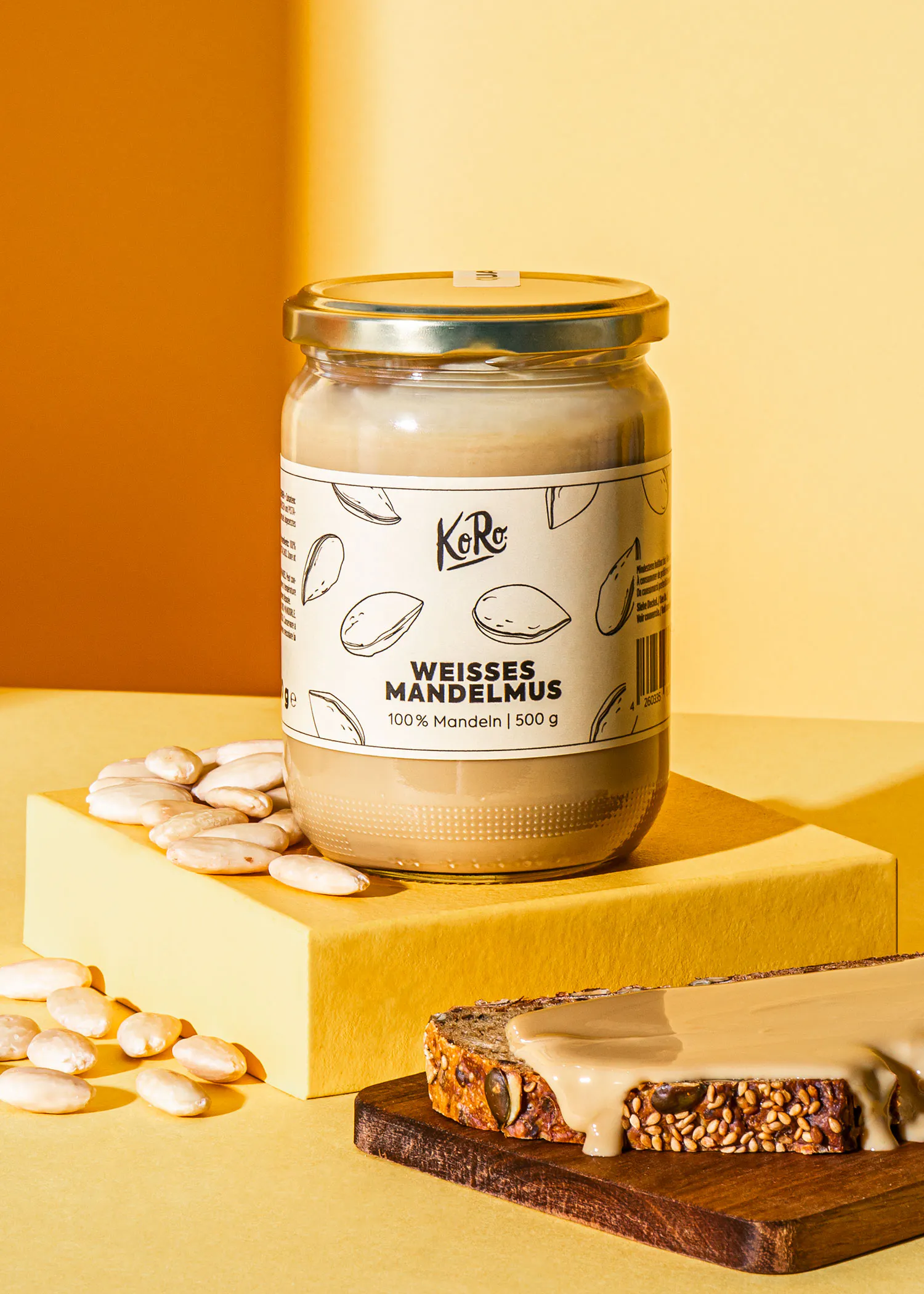 un bocal de sauce aux amandes blanches est assis sur une table jaune à côté d' une tranche de pain