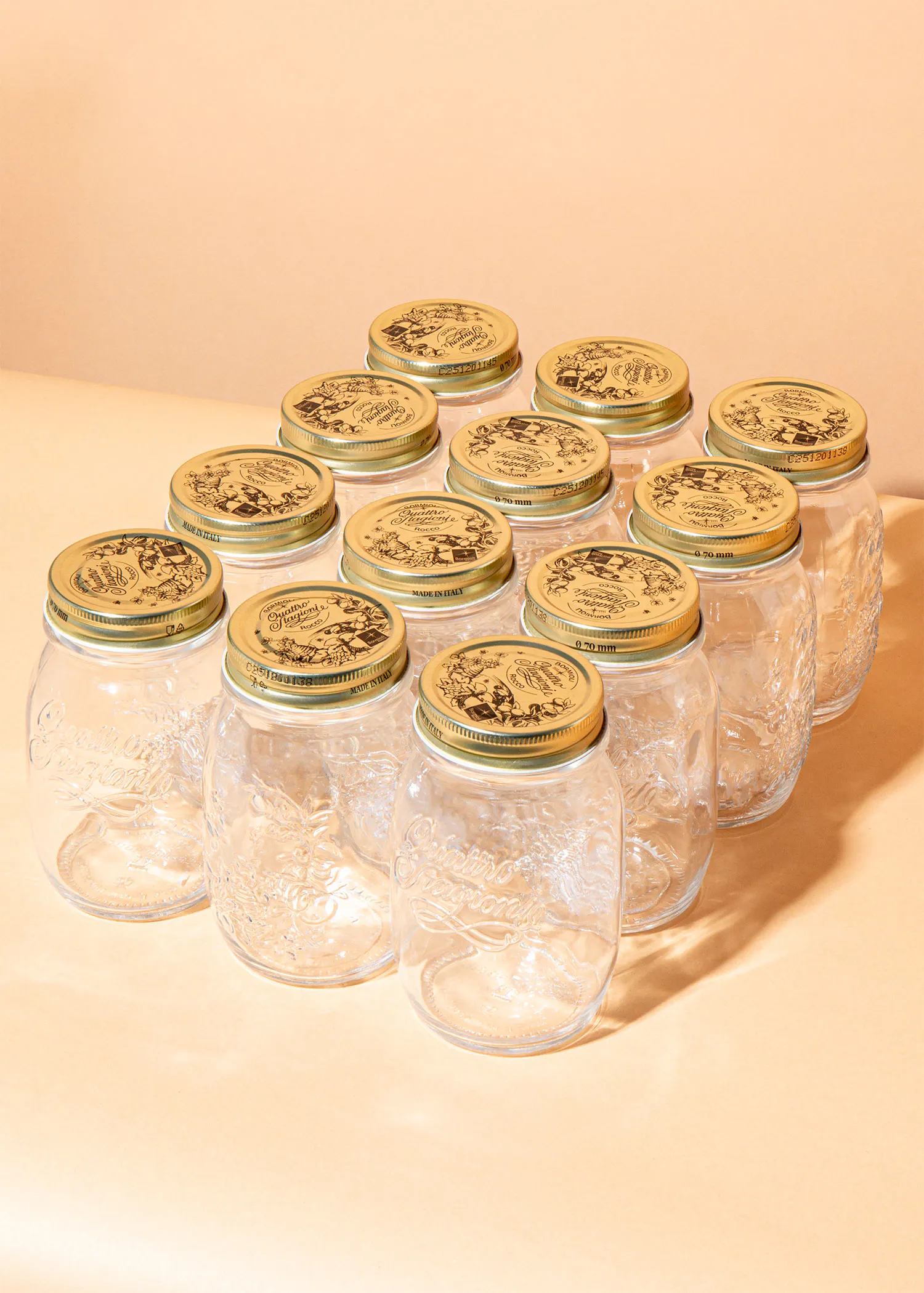 a row of clear jars with gold lids that say ' quattro stagioni ' on them