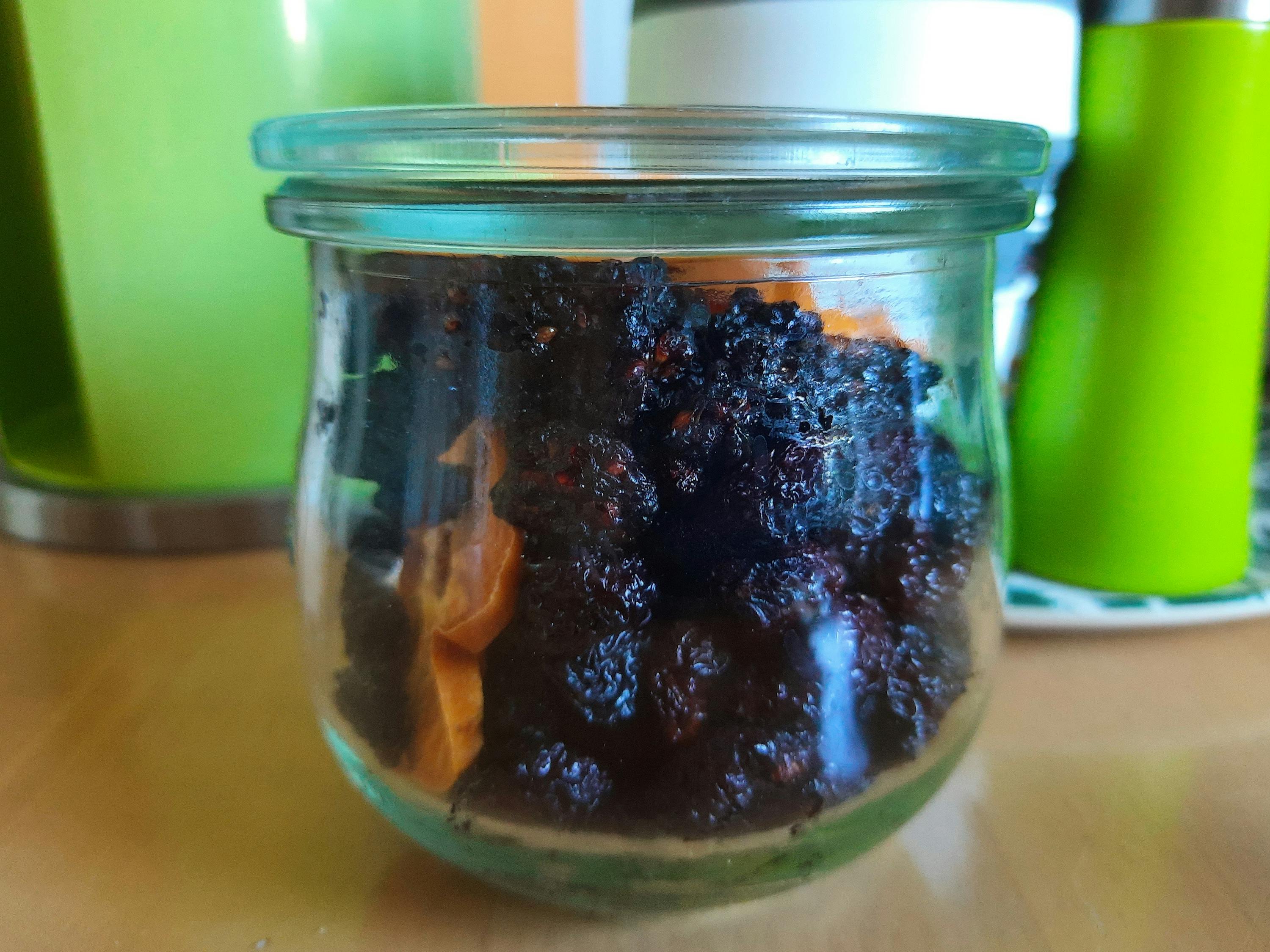 ein Glas gefüllt mit schwarzen Rosinen auf einem Tisch