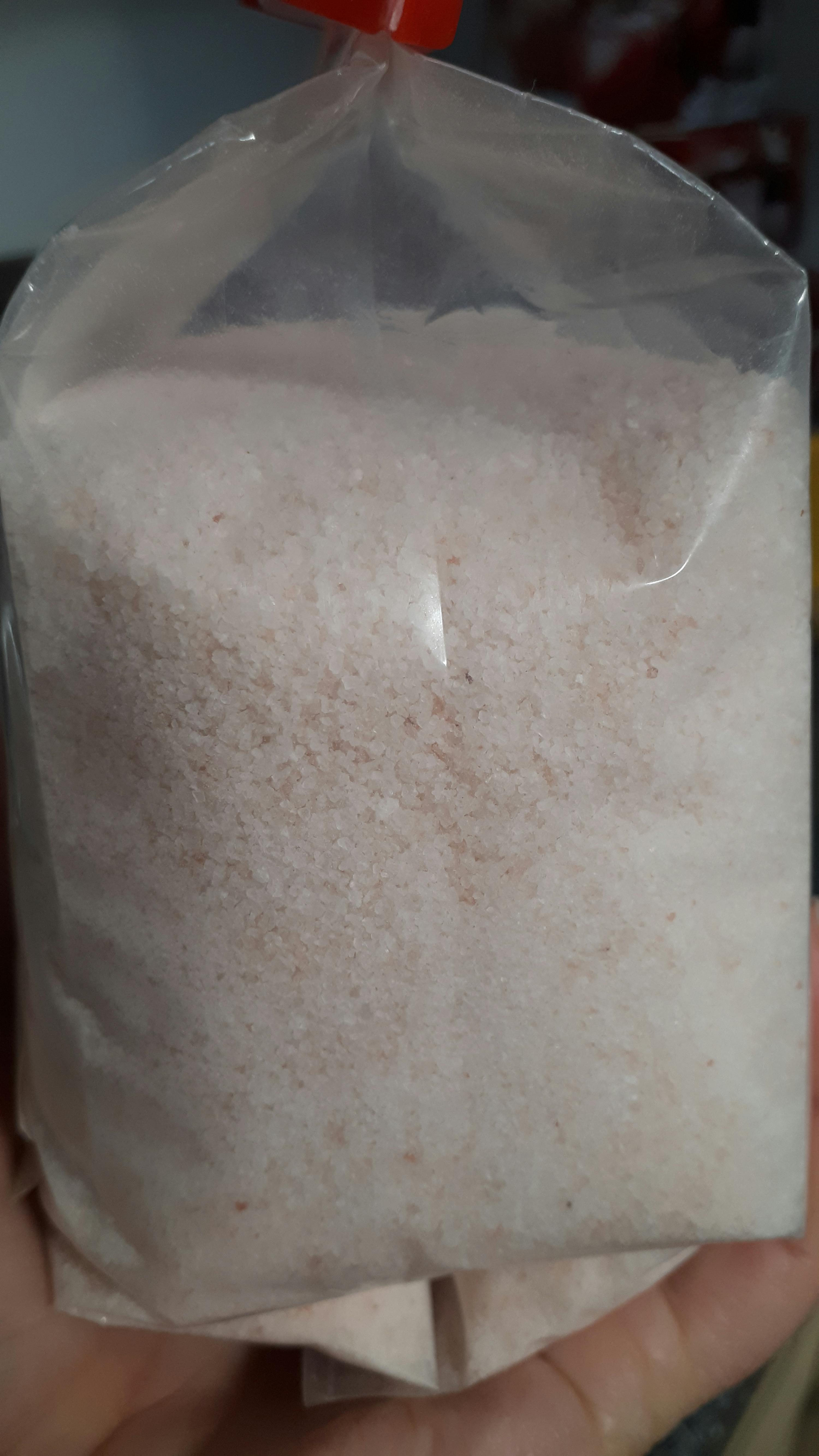 a person is holding a bag of pink salt in their hand