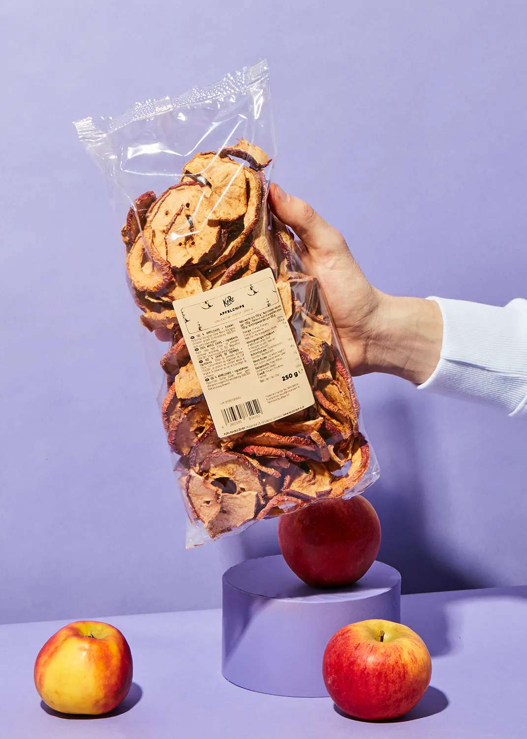 a person is holding a bag of dried apple slices