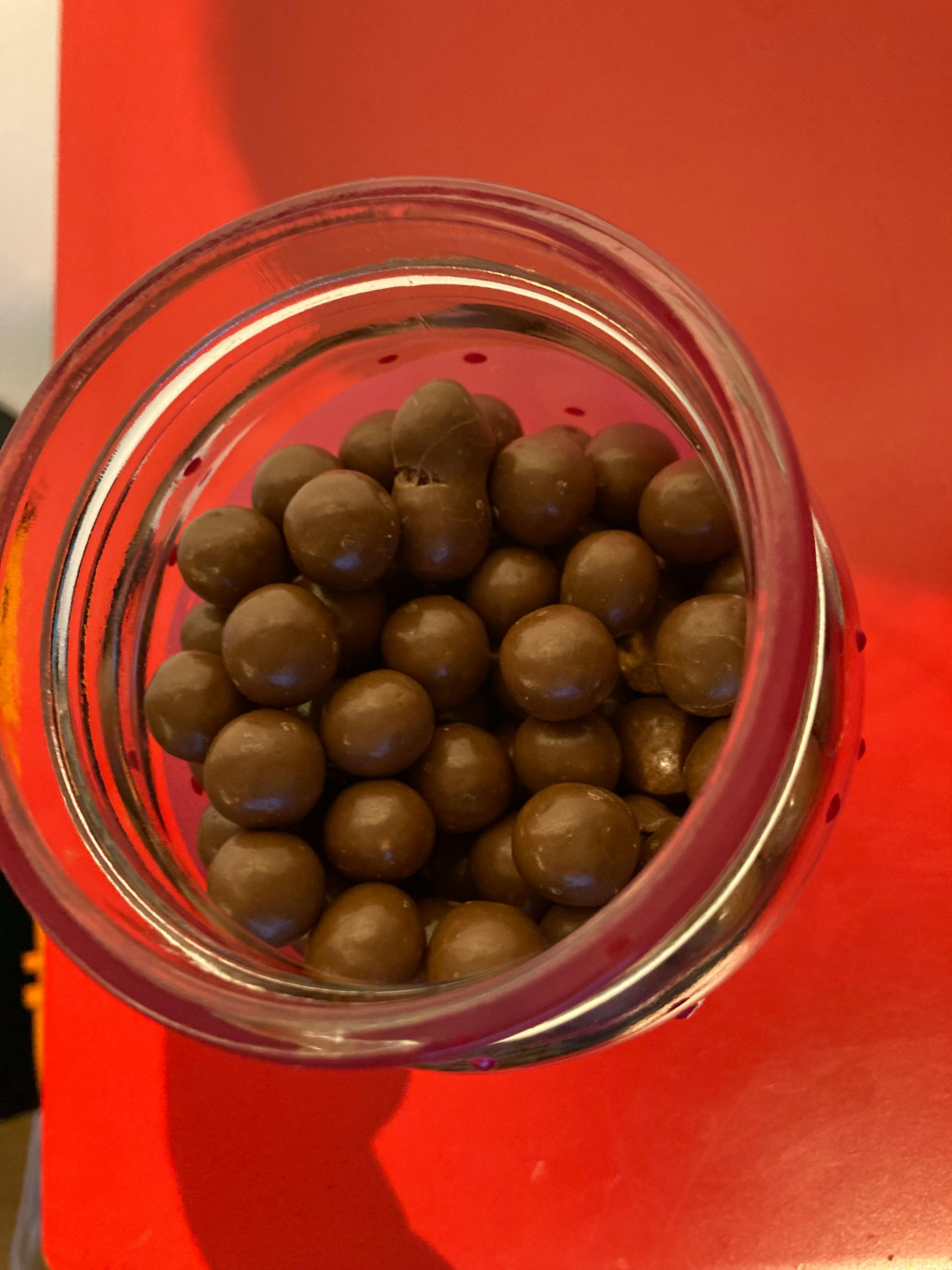 a glass jar filled with chocolate balls on a red table