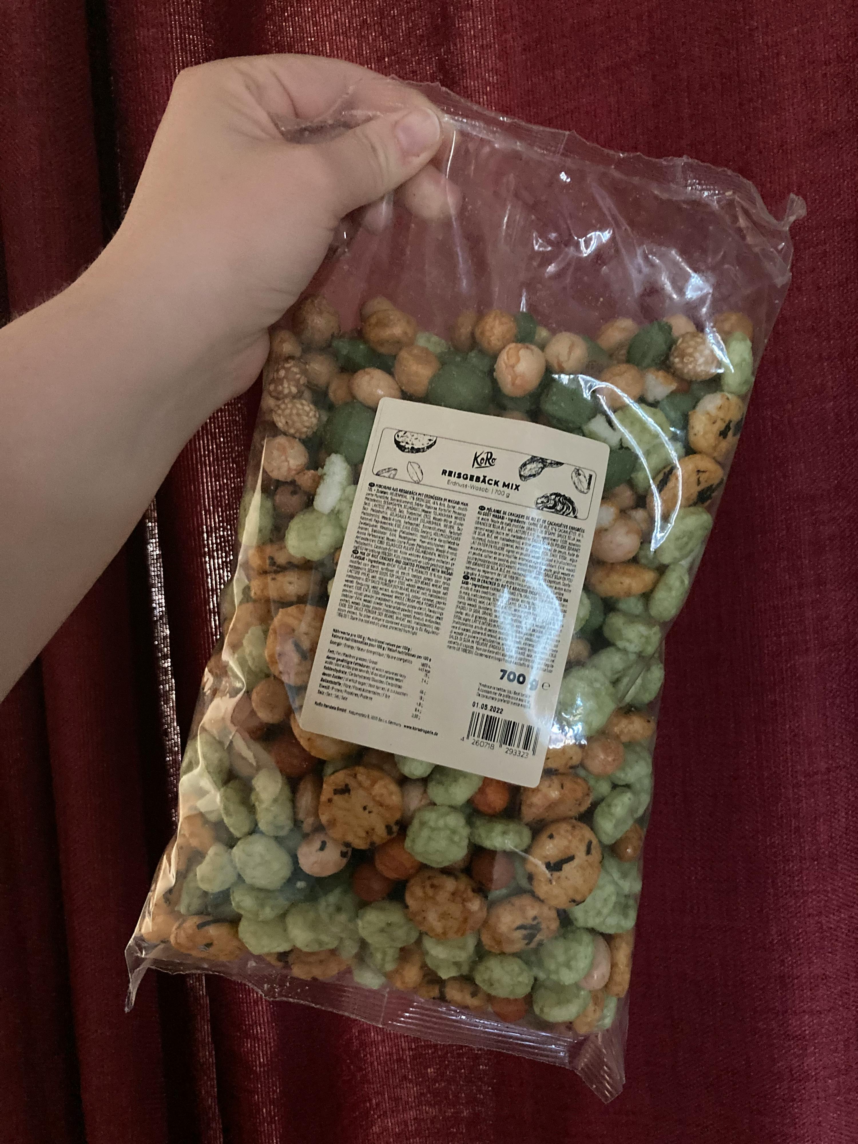a person is holding a bag of kik peanuts