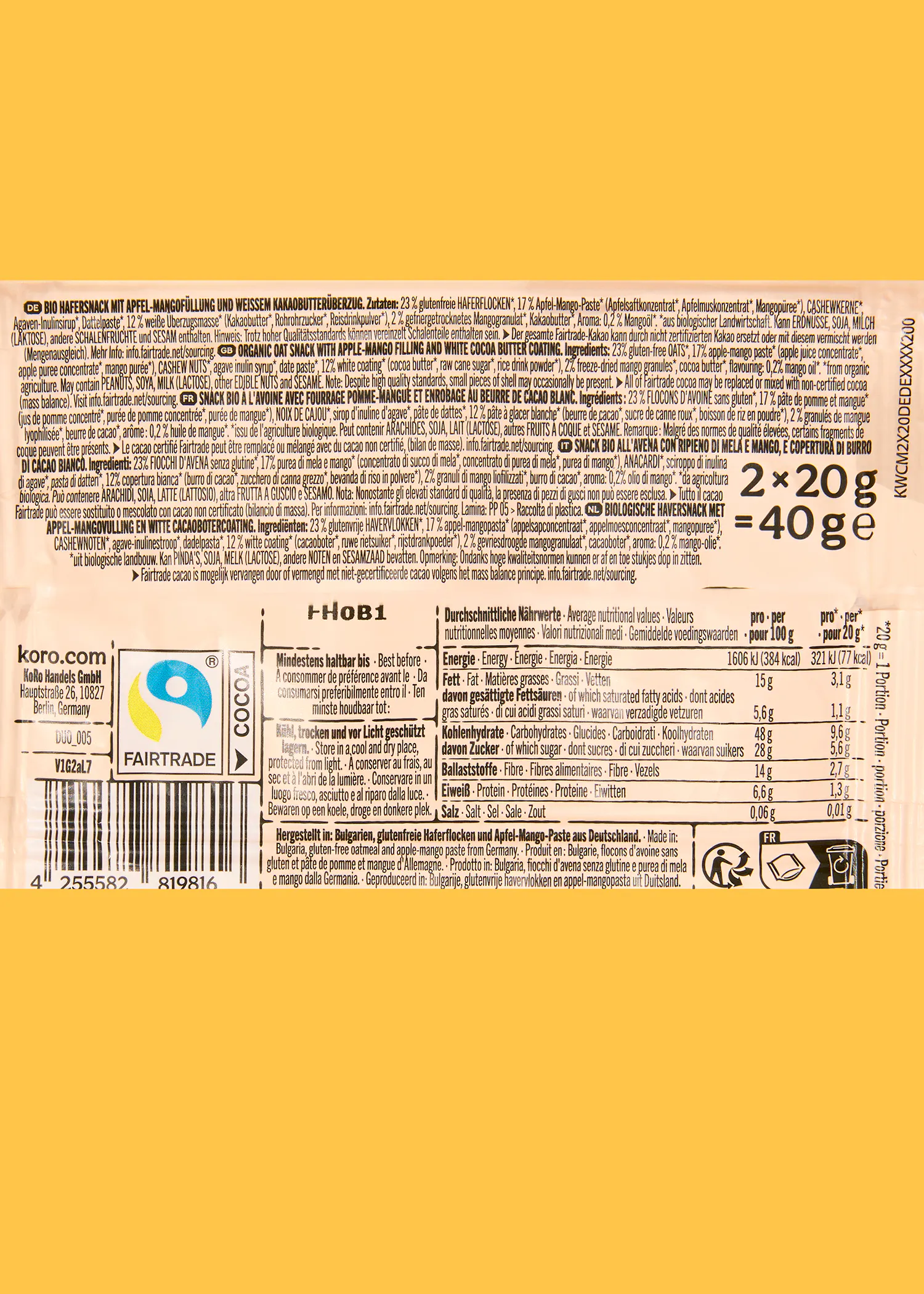 a yellow and white product label for a koro bio oat snack with apple-mango filling and white cocoa butter coating, displaying ingredients, nutritional information, a fairtrade logo, and a barcode in multiple languages.
