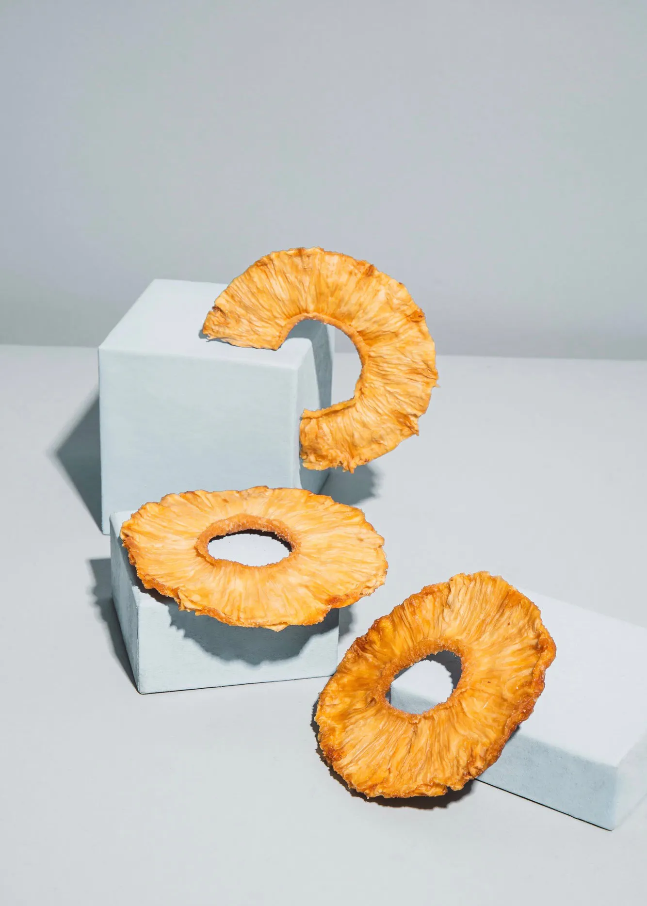 drei Ananasringe sitzen auf einem blauen Block